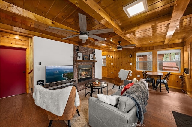 living room with wood walls, wood ceiling, beam ceiling, a stone fireplace, and wood finished floors