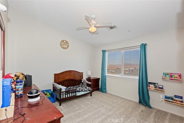 carpeted bedroom featuring a crib, visible vents, and a ceiling fan