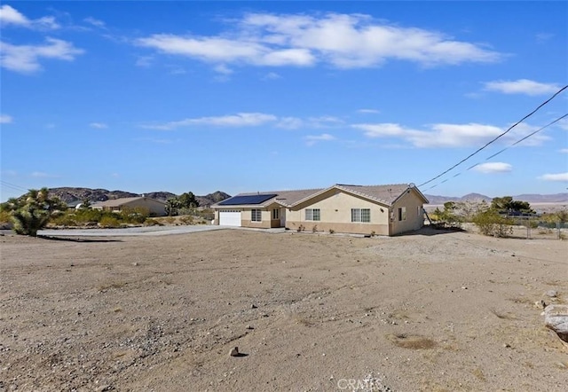 ranch-style home featuring a garage, solar panels, and a mountain view