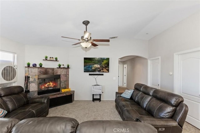 living room featuring light carpet, a tile fireplace, arched walkways, and visible vents