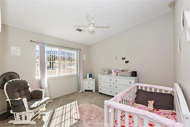 bedroom with visible vents, light carpet, ceiling fan, and a crib