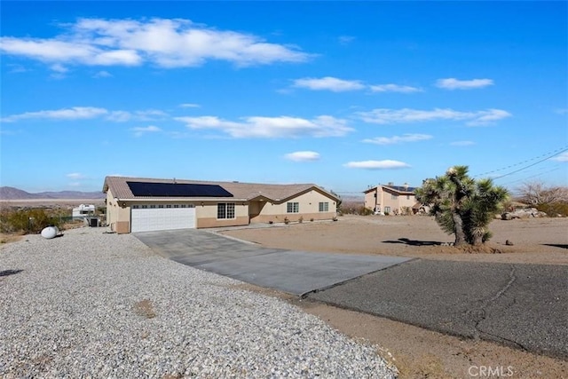 ranch-style home featuring an attached garage, a mountain view, solar panels, and concrete driveway