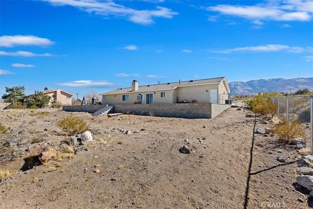 rear view of house with a mountain view and fence