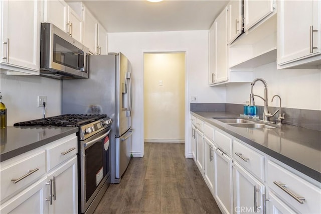 kitchen featuring white cabinets, dark countertops, dark wood-style floors, stainless steel appliances, and a sink