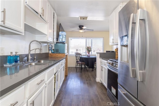 kitchen featuring appliances with stainless steel finishes, dark countertops, white cabinetry, and a sink