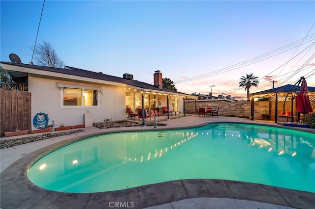 pool at dusk with a gazebo, a patio, fence, and a fenced in pool