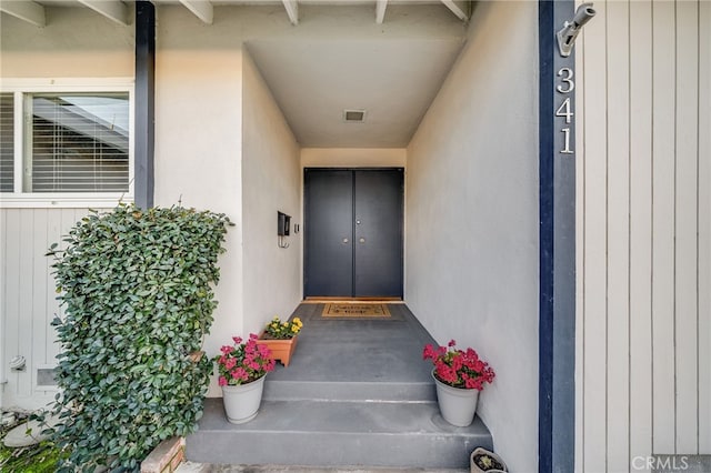 property entrance with visible vents and stucco siding