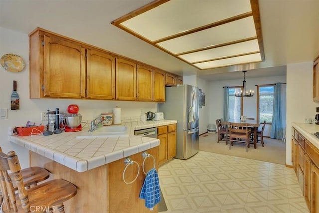 kitchen featuring brown cabinets, hanging light fixtures, a peninsula, and a sink