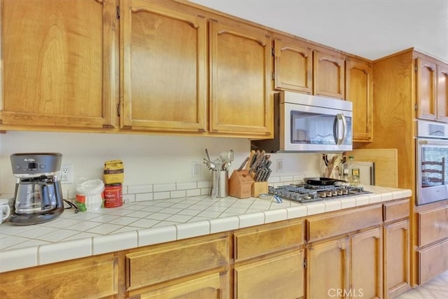 kitchen with tile countertops and appliances with stainless steel finishes