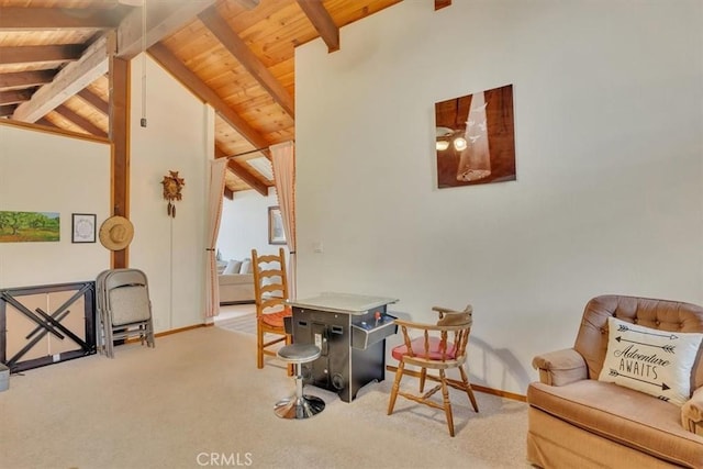 sitting room with wood ceiling, light colored carpet, vaulted ceiling with beams, and baseboards