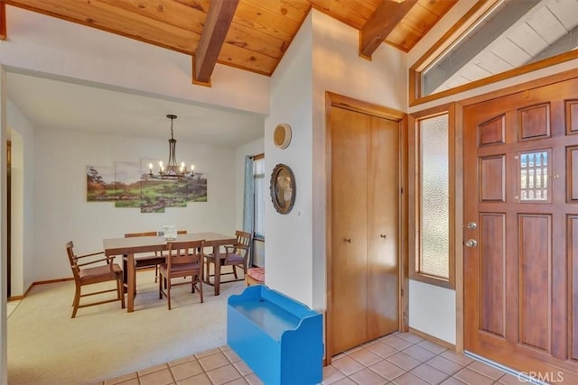 entrance foyer with wooden ceiling, light tile patterned flooring, an inviting chandelier, and light colored carpet