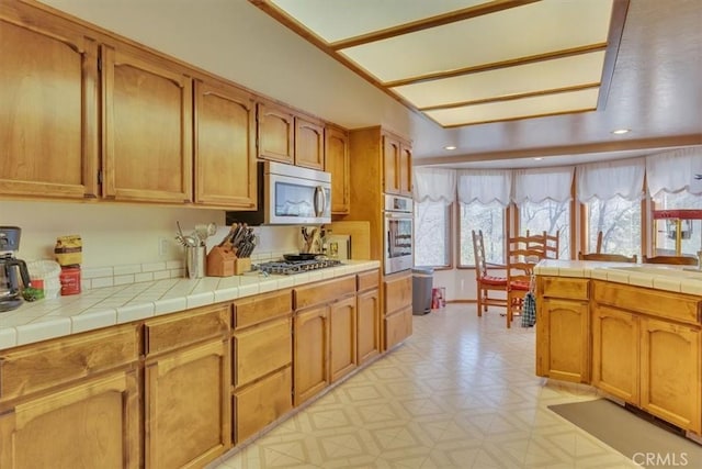 kitchen with stainless steel appliances, tile counters, light floors, and recessed lighting