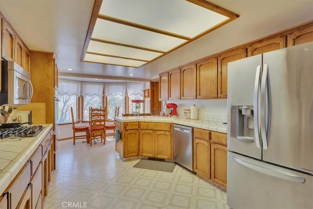 kitchen featuring stainless steel appliances, a peninsula, tile counters, and recessed lighting