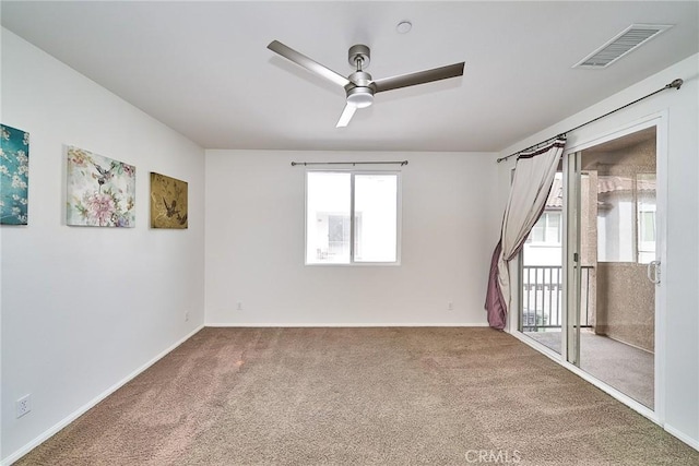 empty room with baseboards, carpet floors, visible vents, and a ceiling fan