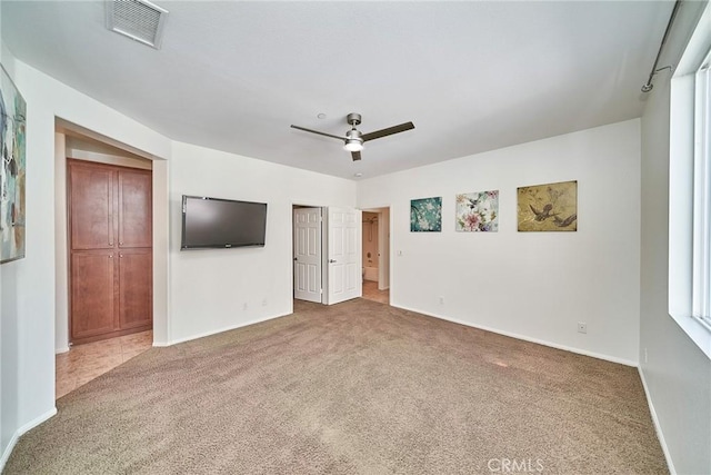 unfurnished bedroom featuring ensuite bathroom, ceiling fan, carpet flooring, visible vents, and baseboards