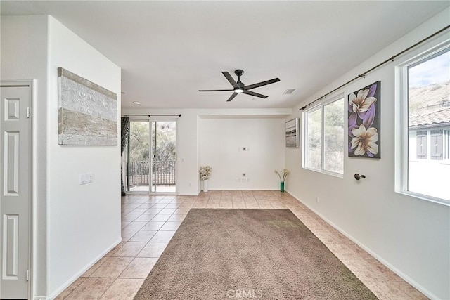 spare room with a healthy amount of sunlight, light tile patterned floors, ceiling fan, and visible vents