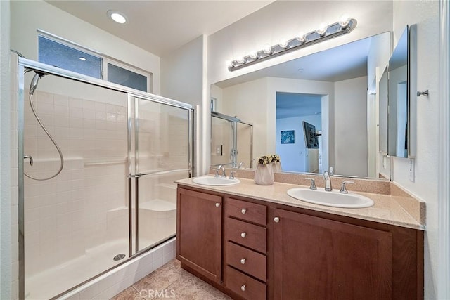 bathroom featuring a stall shower, tile patterned floors, a sink, and double vanity