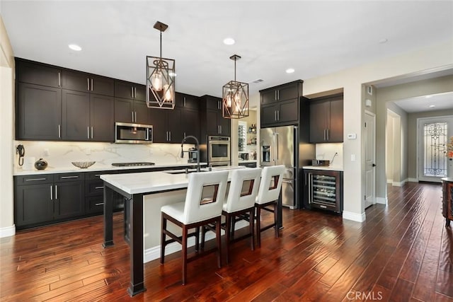 kitchen with dark wood finished floors, light countertops, appliances with stainless steel finishes, a sink, and a kitchen bar