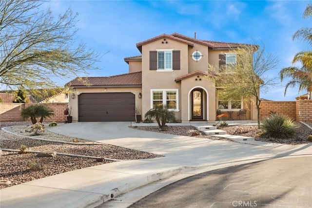 mediterranean / spanish-style home with driveway, a garage, fence, and a tiled roof