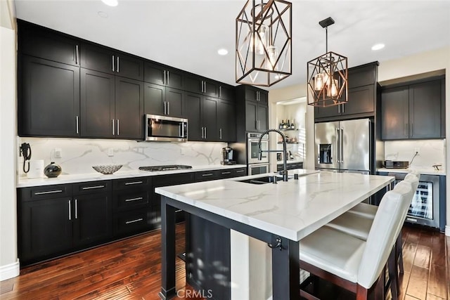 kitchen with stainless steel appliances, tasteful backsplash, dark wood-type flooring, a sink, and dark cabinetry