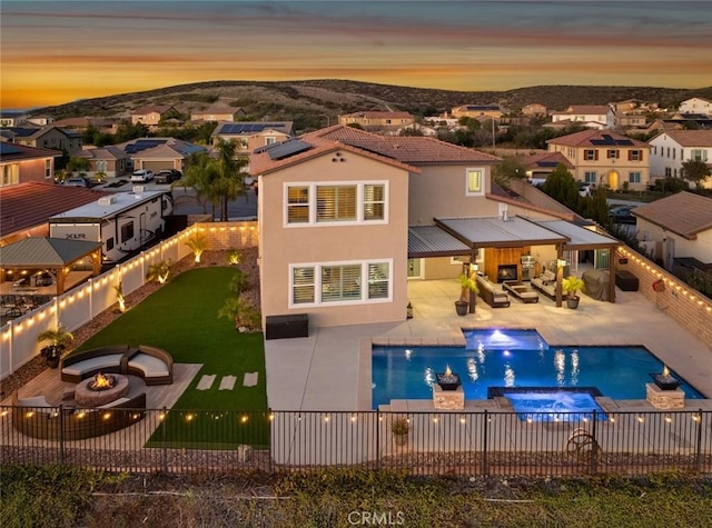 rear view of property featuring an outdoor living space with a fire pit, a fenced backyard, a patio, and stucco siding