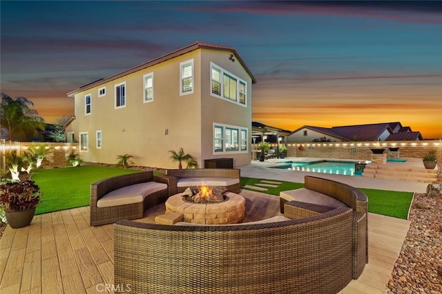 rear view of house featuring a fenced in pool, an outdoor fire pit, a yard, and stucco siding