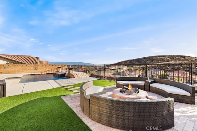 exterior space with fence, a mountain view, and an outdoor living space with a fire pit