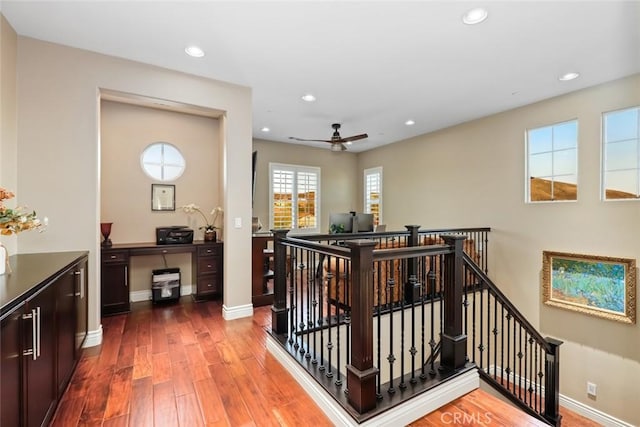 hallway with recessed lighting, wood-type flooring, baseboards, and an upstairs landing