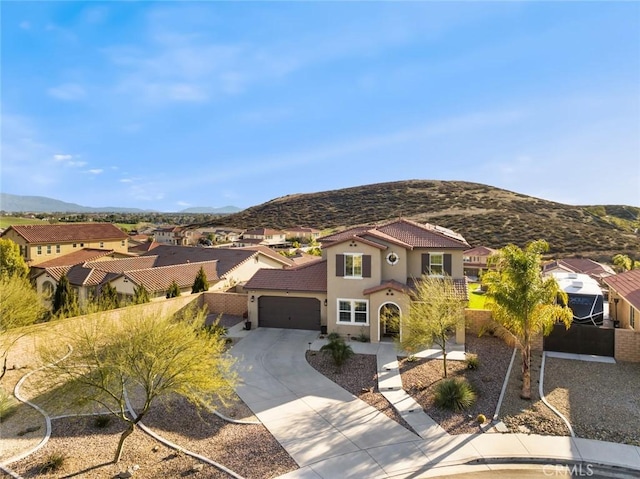 mediterranean / spanish-style home featuring an attached garage, a mountain view, a tile roof, driveway, and stucco siding