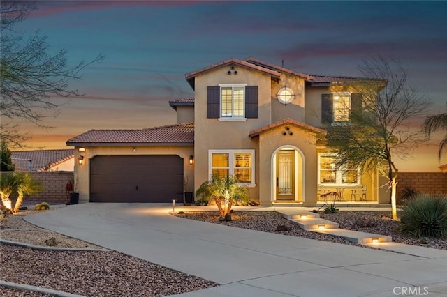 mediterranean / spanish-style home featuring stucco siding, roof mounted solar panels, fence, a garage, and driveway