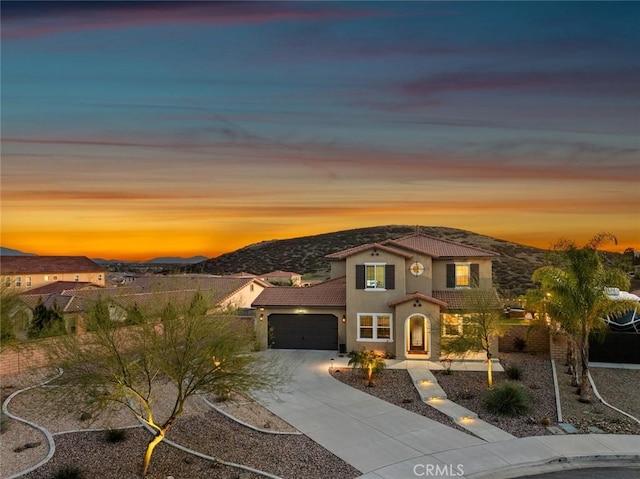 mediterranean / spanish house with a garage, a tile roof, a mountain view, and stucco siding