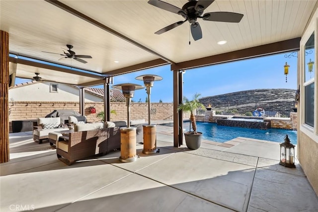 view of patio featuring a ceiling fan, fence, a pool with connected hot tub, a mountain view, and an outdoor living space