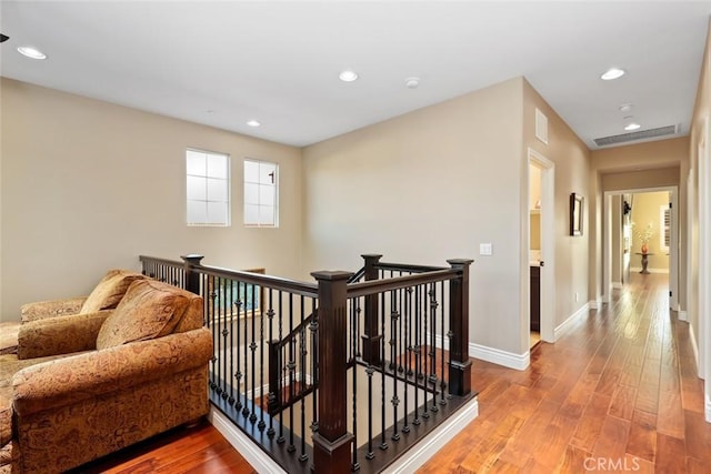 corridor with recessed lighting, hardwood / wood-style floors, and an upstairs landing