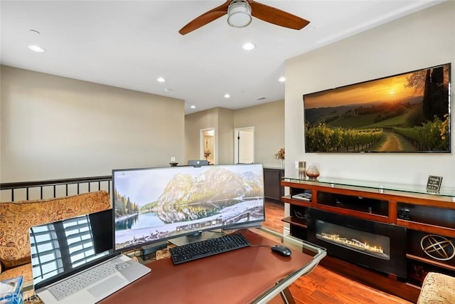 office space featuring a glass covered fireplace, wood finished floors, a ceiling fan, and recessed lighting