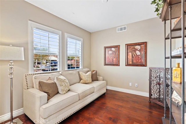 living area with baseboards, visible vents, and dark wood finished floors