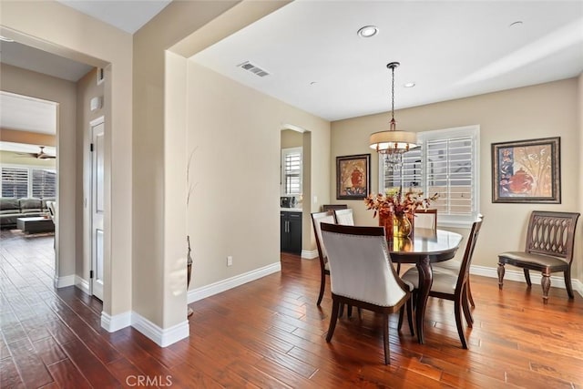 dining area with dark wood finished floors, visible vents, and baseboards