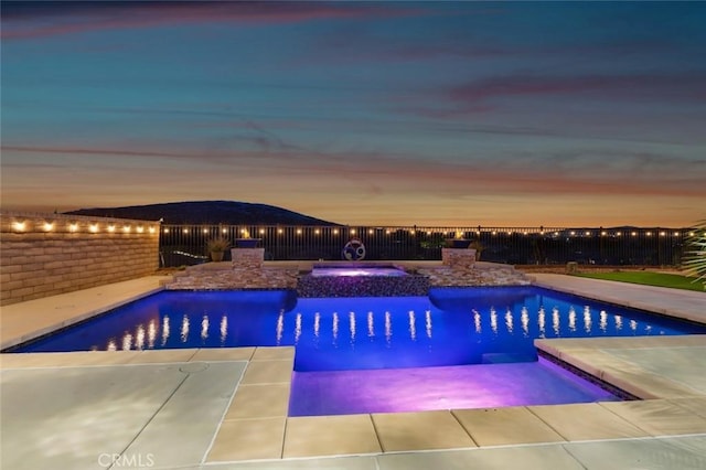 view of swimming pool with fence and a pool with connected hot tub