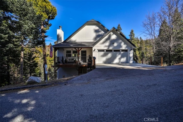 28622 Shenandoah Dr, Lake Arrowhead, CA 92352 - chalet / cabin featuring an attached garage, a chimney, asphalt driveway, and covered porch