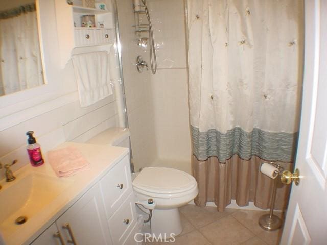 bathroom with toilet, vanity, and tile patterned floors