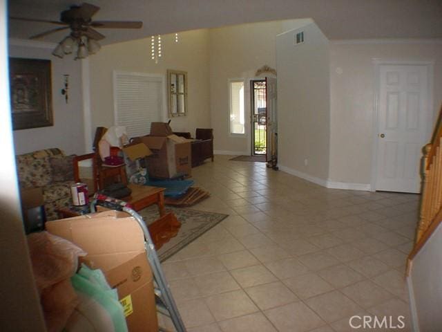 living area with visible vents, a ceiling fan, ornamental molding, light tile patterned flooring, and baseboards