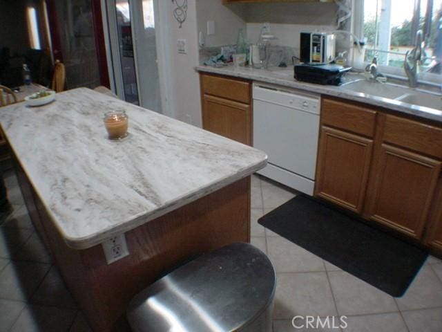 kitchen featuring light countertops, white dishwasher, a sink, and a center island