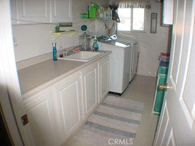 laundry room with washer and clothes dryer, a sink, and cabinet space