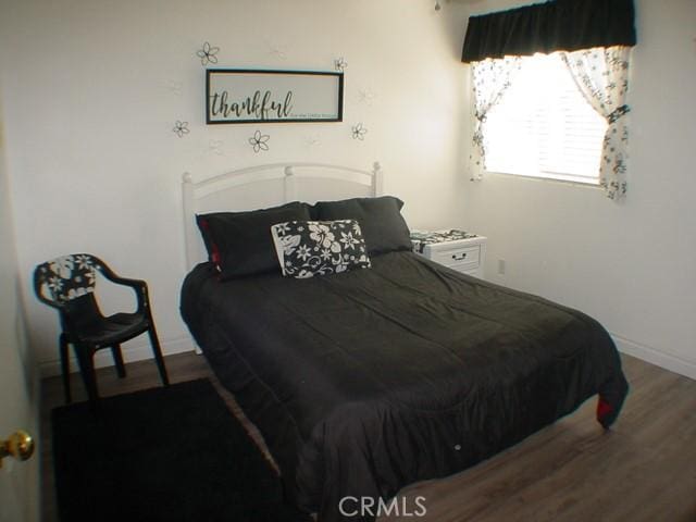 bedroom featuring wood finished floors and baseboards