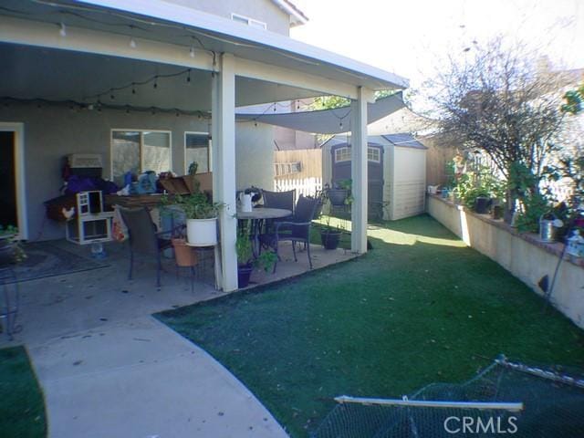 view of yard with an outbuilding, a patio, a shed, and fence private yard