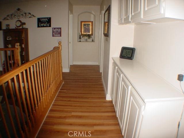 hallway featuring baseboards, an upstairs landing, and light wood-style floors