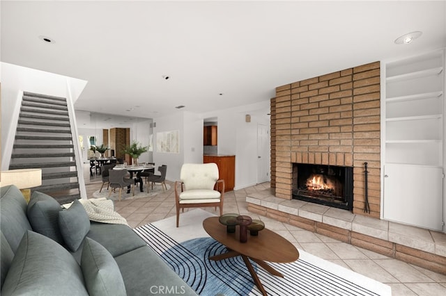 living room featuring light tile patterned floors, built in shelves, and a brick fireplace