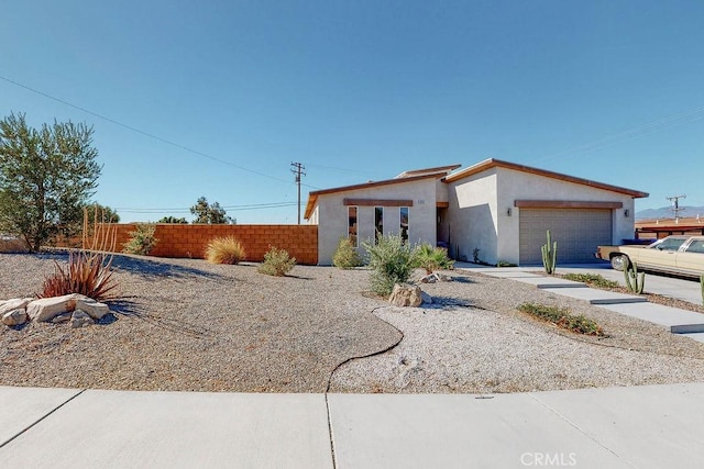 view of front of property featuring a garage, fence, driveway, and stucco siding