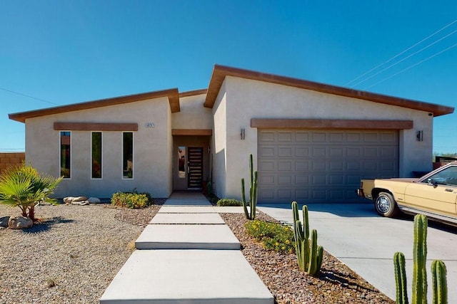 view of front of home with concrete driveway, an attached garage, and stucco siding