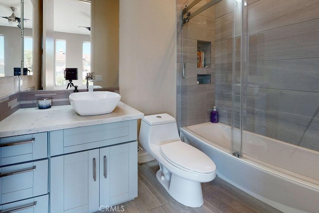 bathroom featuring bath / shower combo with glass door, toilet, a ceiling fan, vanity, and wood finished floors