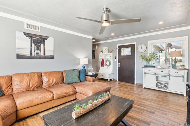 living area with crown molding, recessed lighting, visible vents, light wood-style floors, and a ceiling fan